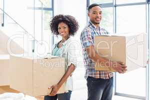 Smiling young couple holding a carton in their new house