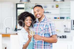 Happy couple toasting champagne glass in kitchen