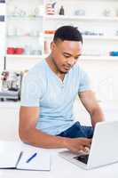 Happy young man using laptop in kitchen