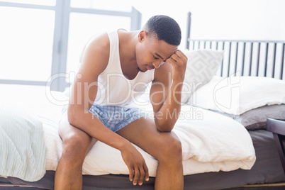 Tensed young man sitting on bed