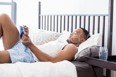 Happy young man using digital tablet on bed