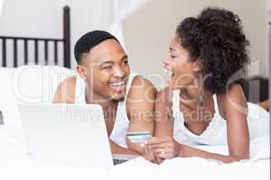 Happy couple shopping online through laptop using credit card