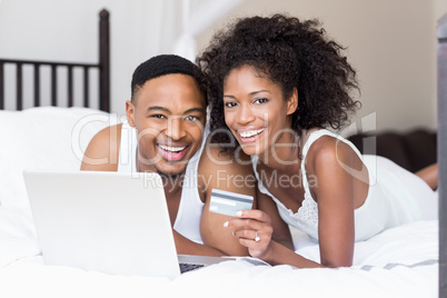 Happy couple shopping online through laptop using credit card