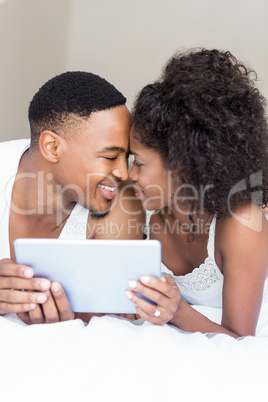 Young couple cuddling each other while holding digital tablet
