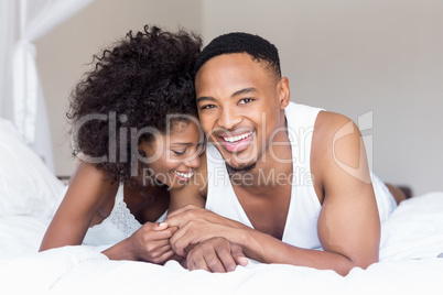 Young couple lying on bed and embracing each other