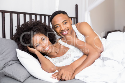 Young couple lying on bed and cuddling each other
