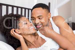 Young couple lying on bed and cuddling each other