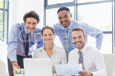 Portrait of happy business colleagues reviewing a report at desk