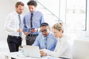 Business colleagues using laptop and digital tablet at desk