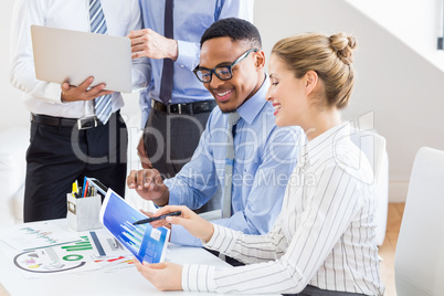 Happy business colleagues reviewing a report at desk