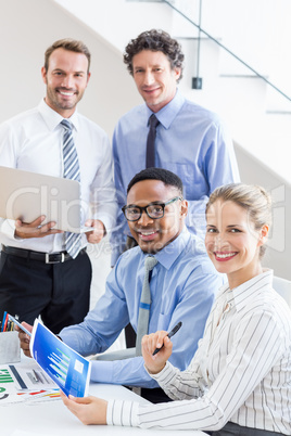 Happy business colleagues reviewing a report at desk