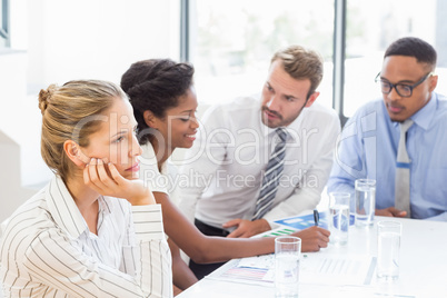 Businesswoman day dreaming while colleague discussing in backgro