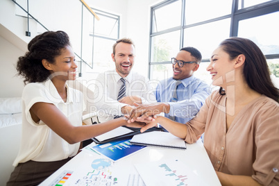 Smiling businesspeople putting their hands together during a mee