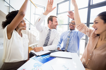 Happy businesspeople raising their hands during a meeting