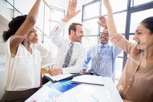 Happy businesspeople raising their hands during a meeting