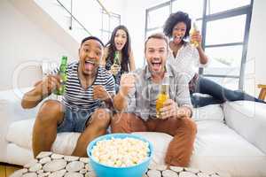 Friends sitting on sofa and holding beer bottles