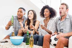 Friends sitting on sofa and watching television