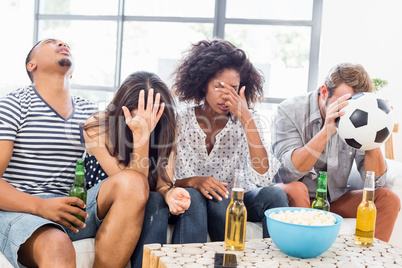 Friends sitting on sofa and watching television