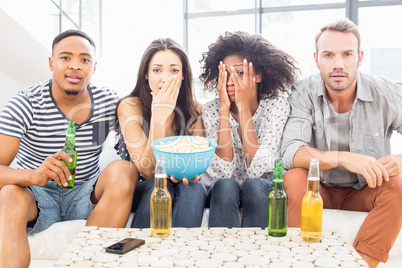 Friends sitting on sofa and having beer and popcorn