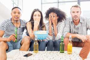 Friends sitting on sofa and having beer and popcorn