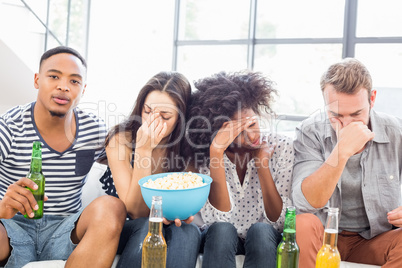 Friends sitting on sofa with a bowl of popcorn