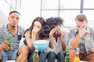 Friends sitting on sofa with a bowl of popcorn