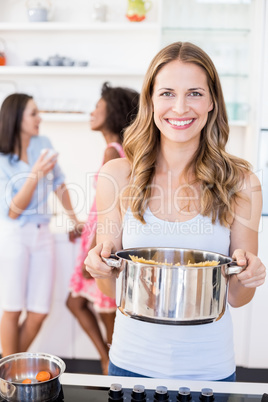 Woman holding a vessel while preparing meal in kitchen