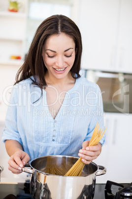 Woman preparing spaghetti noodles in kitchen