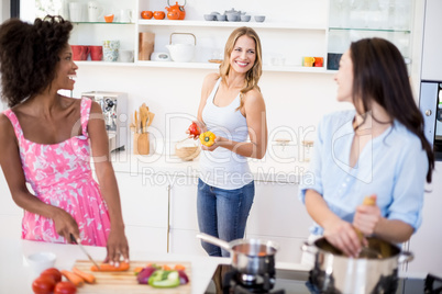 Friends interacting while preparing a meal in kitchen