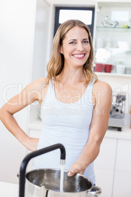 Woman holding a vessel under running tap