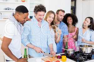 Friends having alcoholic beverage and preparing meal in kitchen