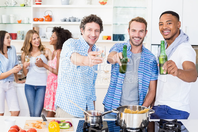 Friends toasting beer and wine glass in kitchen