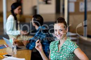 Young woman holding spectacles smiling at camera