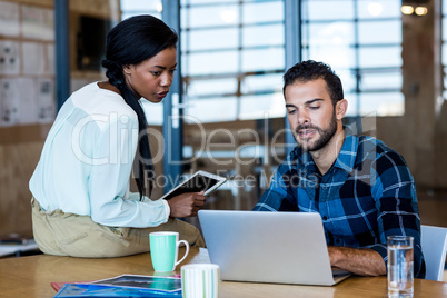 Young man and woman discuss using digital tablet and laptop