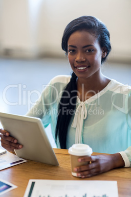 Businesswoman holding disposable coffee cup and digital tablet