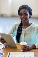 Businesswoman holding disposable coffee cup and digital tablet