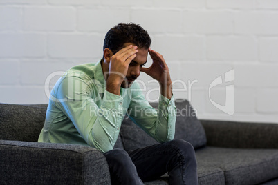 Frustrated young man sitting on sofa