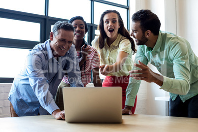 Colleagues discussing using laptop