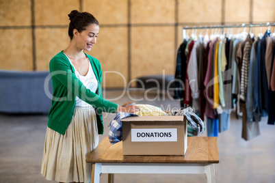 Young woman sorting clothes from donation box
