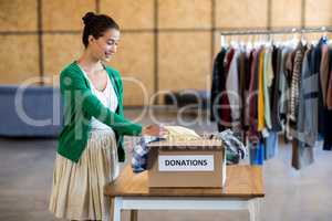 Young woman sorting clothes from donation box