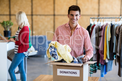 Young man sorting clothes from donation box