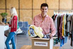 Young man sorting clothes from donation box