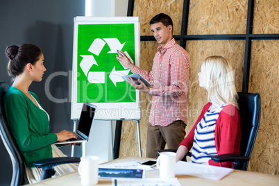 Colleagues discussing with recycling sign on white board