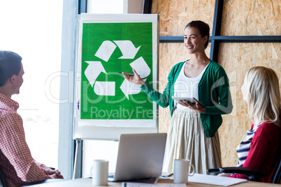 Colleagues discussing with recycling sign on white board
