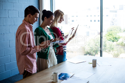 Colleagues using mobile phone, digital tablet and laptop at thei