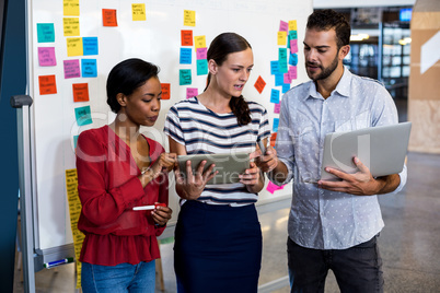 Colleagues discussing using digital tablet and laptop