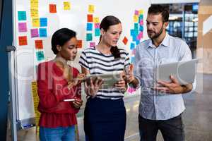 Colleagues discussing using digital tablet and laptop