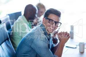 Young man sitting at his desk smiling at camera