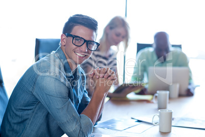 Young man sitting at his desk smiling at camera