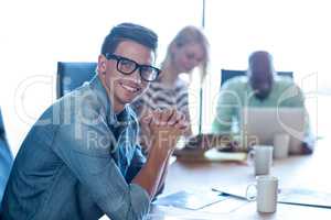 Young man sitting at his desk smiling at camera